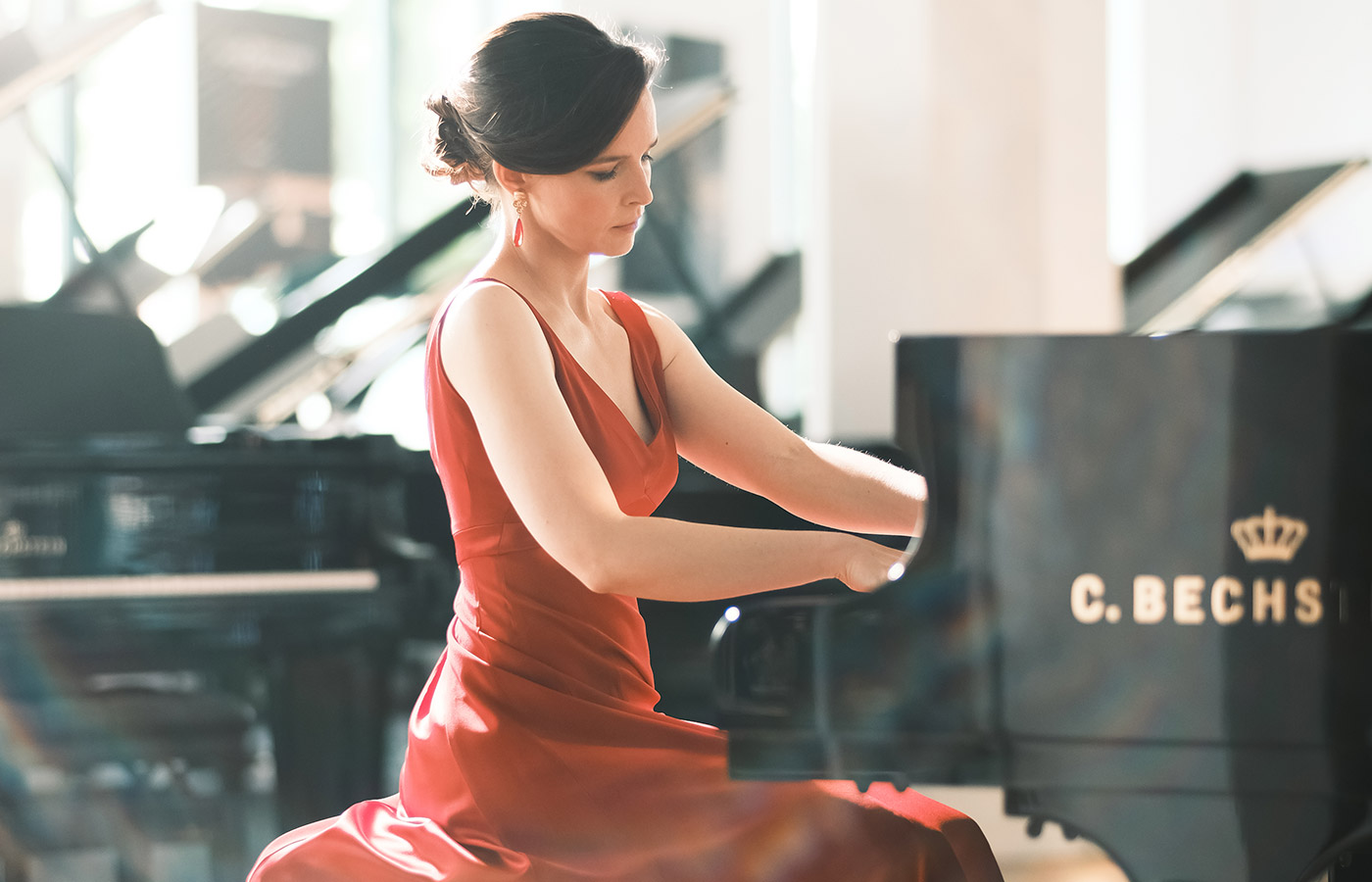 Pianistin Sophie Weidemann in einem roten Konzertkleid am Flügel